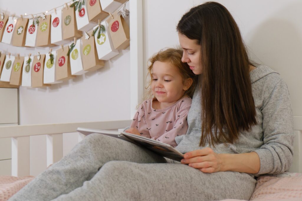 Mather with toddler child reading book on Christmas eve