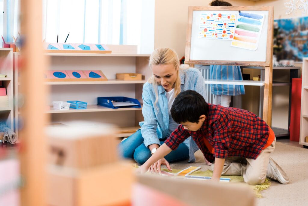 Selective focus of teacher playing with kid in montessori school